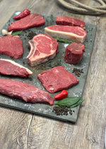 Variety of Beef Cuts on a piece of slate surrounded by seaosonings